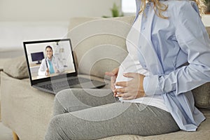 Young pregnant woman having telemedicine consultation with online doctor on laptop