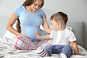 Young pregnant woman with her cute little son at home