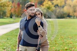 Young pregnant woman and her handsome husband are walking at the autumn park.