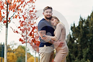 Young pregnant woman and her handsome husband are walking at the autumn park.