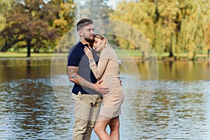 Young pregnant woman and her handsome husband are walking at the autumn park.