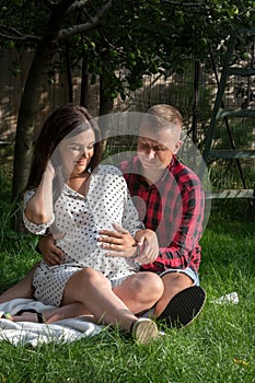 A young pregnant woman and her husband are in the garden