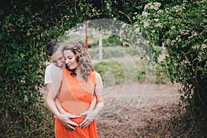 Young pregnant woman with her husband holding hands on her belly