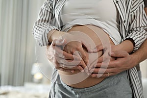 Young pregnant woman with her husband at home, closeup