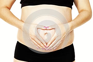 Young pregnant woman holding her hands in a heart