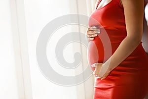 Young pregnant woman holds her hands on her big belly. Love concept