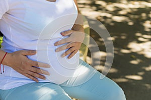 A young pregnant woman holds her hands on her tummy and feels the tremors of her baby