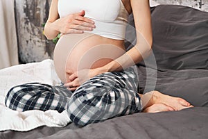 A young pregnant woman holds on to her stomach