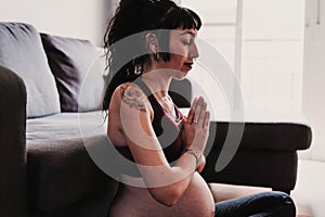 Young pregnant woman at home doing yoga