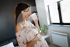 Young pregnant woman at home sipping tea from a cup