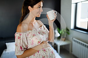 Young pregnant woman at home sipping tea from a cup