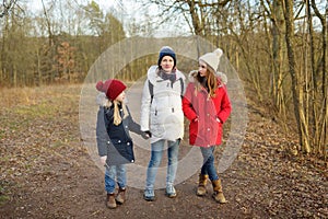 Young pregnant woman hugging her older daughters. Older siblings having fun with her pregnant mom outdoors. Mother and her kids