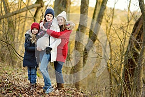 Young pregnant woman hugging her older daughters. Older siblings having fun with her pregnant mom outdoors. Mother and her kids