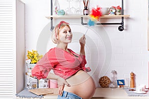 Young pregnant woman iinduces cleanliness in the kitchen with pipidaster