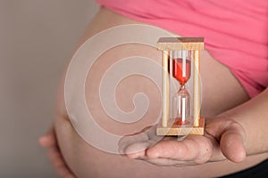 Young pregnant  woman keeps sandwatch close to her belly