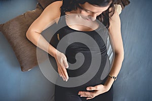 young pregnant woman laying on bed and relaxing, talking to the baby