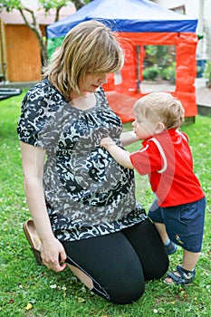 Young pregnant woman and little son in summer garden