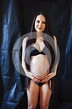 young pregnant woman with long hair on black background, lifesty