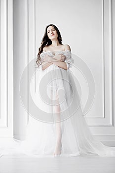 young pregnant woman in long white negligee