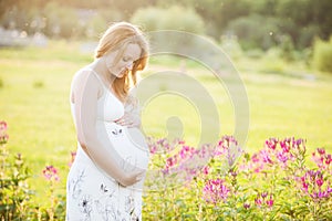 Young pregnant woman looking at her belly in park