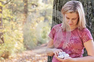 Young pregnant woman in looking at knitted baby booties outdoors