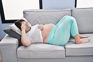 Young pregnant woman lying on sofa resting at home