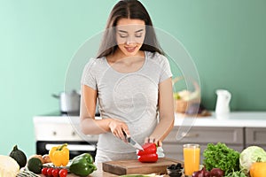 Young pregnant woman making fresh vegetable salad in kitchen