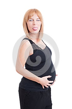 Young pregnant woman making funny face by sticking tongue out