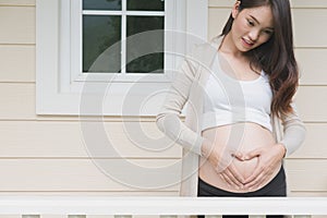 young pregnant woman making heart shape sign on her tummy in fro