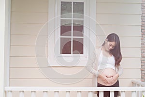 young pregnant woman making heart shape sign on her tummy in fro