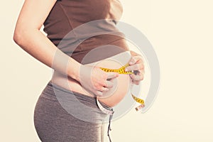 Young pregnant woman measures her belly