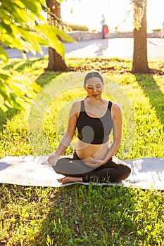 Young pregnant woman meditating in nature, practice yoga. Care of health and pregnancy