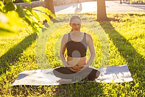 Young pregnant woman meditating in nature, practice yoga. Care of health and pregnancy