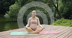 young pregnant woman meditating in nature, practice yoga. Care of health and pregnancy