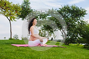 Young pregnant woman meditating in yoga pose