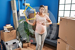 Young pregnant woman moving to a new home clueless and confused expression