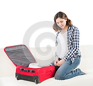 Young pregnant woman packing on a sofa
