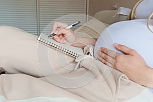 Young Pregnant woman packing suitcase for maternity hospital at home, closeup. Checklist for childbirth. Pregnancy