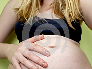 Young pregnant woman, in pain with labor contraction, sitting on bed in bedroom, preparing to give a birth