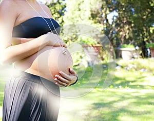 Young pregnant woman at park touching her belly