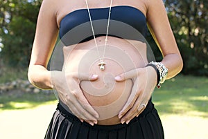 Young pregnant woman at park touching her belly