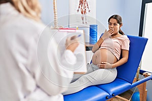 Young pregnant woman at physiotherapist clinic looking at the camera blowing a kiss being lovely and sexy