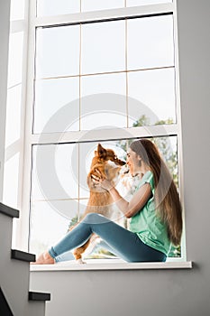 Young pregnant woman play with lovely Welsh Corgi Pembroke in break at online work. Lifestyle with domestic pet