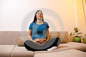 Young pregnant woman practicing breathing techniques in her home
