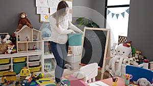Young pregnant woman preschool teacher collecting toys suffering backache at kindergarten