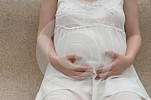 Young pregnant woman putting hands on belly