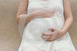 Young pregnant woman putting hands on belly feeling the baby