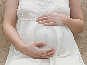 Young pregnant woman putting hands on belly feeling her baby