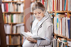 Young pregnant woman reading book