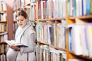 Young pregnant woman reading book